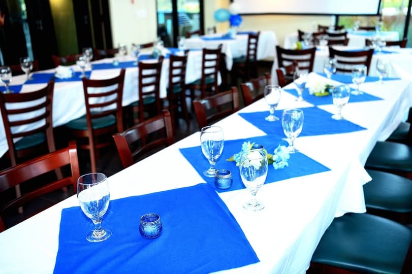 Long banquet table with white and blue linens set for a large catered event