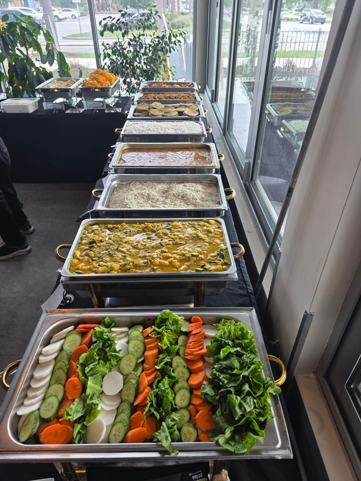 Buffet line of chafing dishes with curries, rice, and fresh salads at a wedding