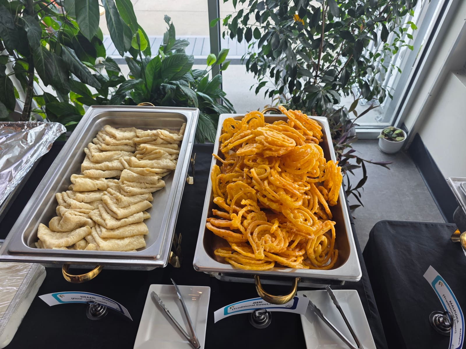 Trays of steamed momo dumplings and fresh jalebi sweets on a buffet table